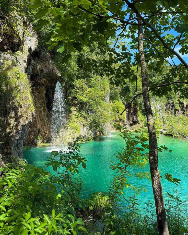 Small waterfall flowing into a turquoise pool surrounded by forest at Plitvice Lakes National Park, Croatia.